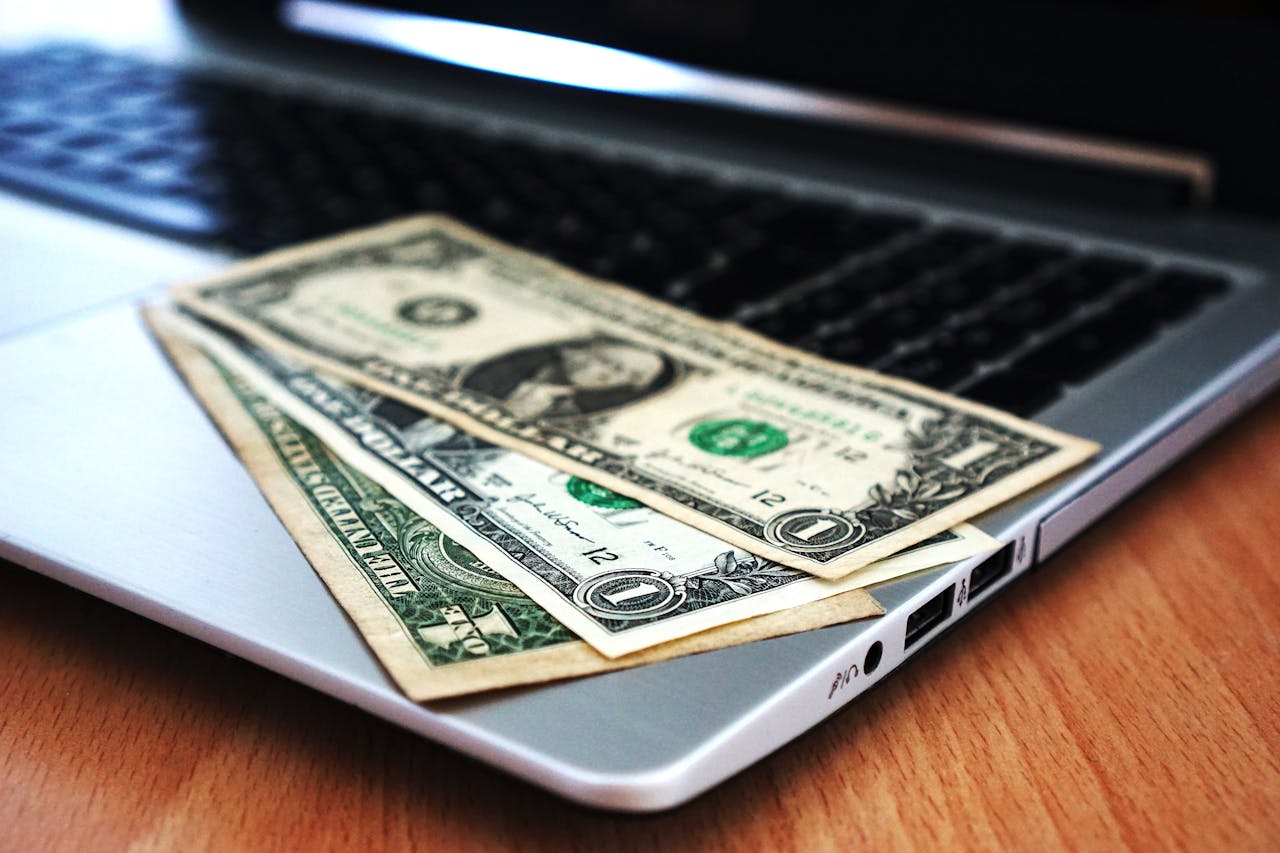 Mastering the First Impression: Your intriguing post title goes here Close-up of US dollar bills placed on a laptop symbolizing digital finance and economy.