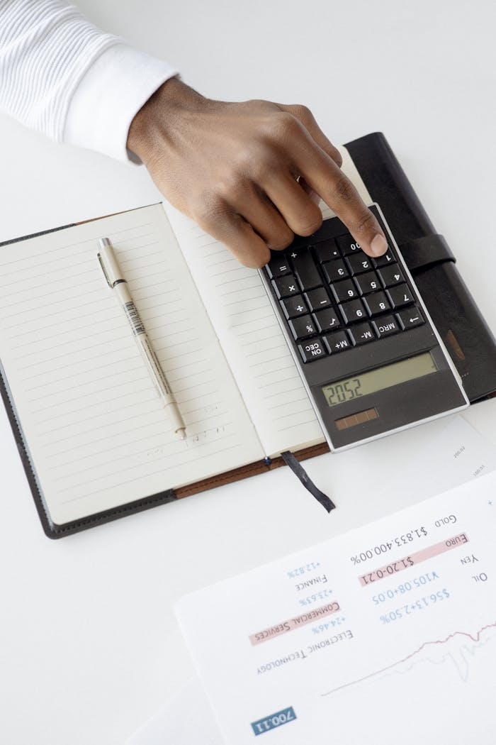 The Art of Drawing Readers In: Your attractive post title goes here A hand using a calculator with financial documents and notebook, depicting an office setup for financial analysis.